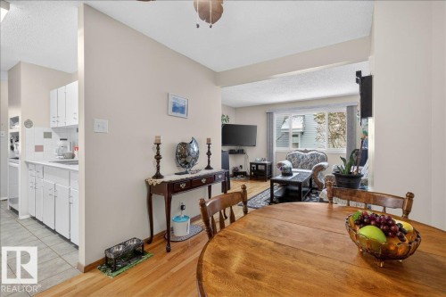 This inviting space features a dining area with hardwood flooring, leading into a living area with a window providing outdoor views - 2 Mcleod Place, Edmonton, AB - Indoor Photo Showing Dining Room