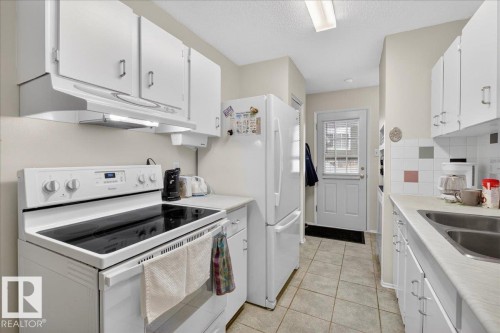 The kitchen features white cabinetry, a dual basin sink, and tile flooring - 2 Mcleod Place, Edmonton, AB - Indoor Photo Showing Kitchen With Double Sink