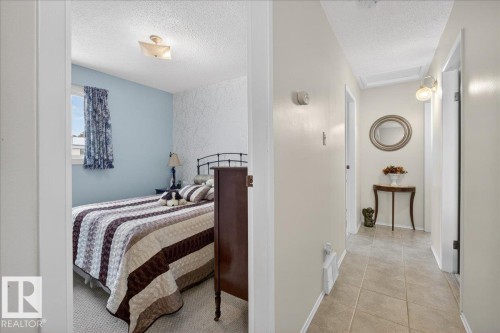 This property features a bedroom with a window, a light blue wall, and a textured accent wall - 2 Mcleod Place, Edmonton, AB - Indoor