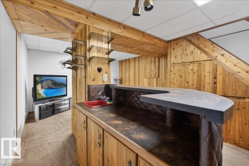 This recreation space features extensive wood paneling, a built-in bar with a sink, and shelving - 2 Mcleod Place, Edmonton, AB - Indoor