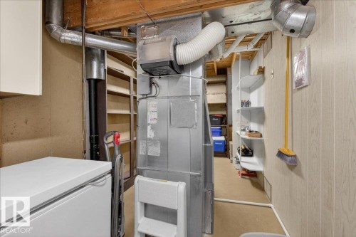 The property includes a utility area with exposed ceiling beams and ductwork, a large utility unit, and shelving for storage - 2 Mcleod Place, Edmonton, AB - Indoor Photo Showing Basement