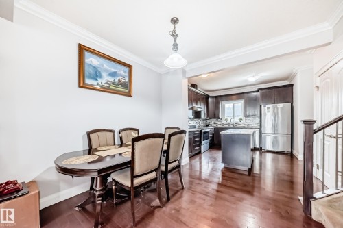 The property features rich hardwood flooring throughout the dining area and kitchen, complemented by white crown molding - 2 12042 101 Street, Edmonton, AB - Indoor Photo Showing Dining Room