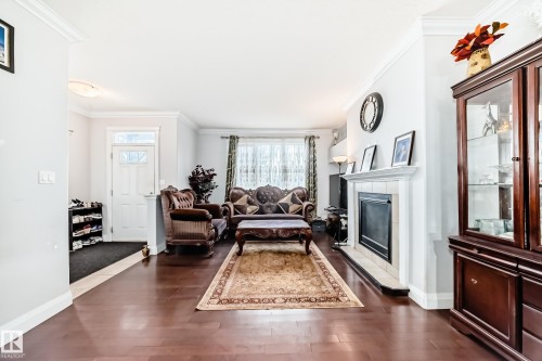 This living area features rich hardwood flooring and a fireplace with a tiled surround - 2 12042 101 Street, Edmonton, AB - Indoor Photo Showing Living Room With Fireplace