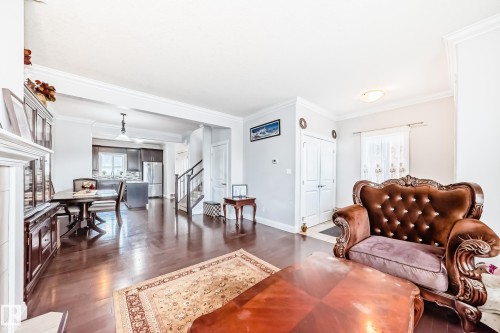 The interior features hardwood flooring, white walls, and a staircase with dark wood handrails - 2 12042 101 Street, Edmonton, AB - Indoor Photo Showing Living Room