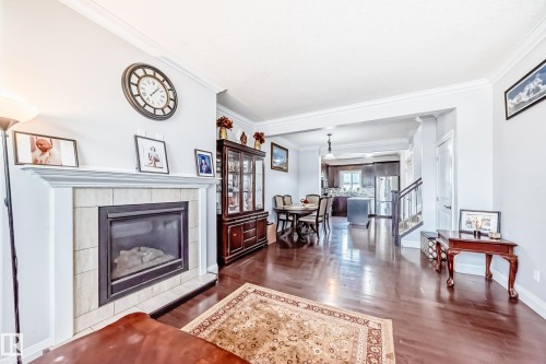 The living area features hardwood floors, a tiled fireplace with a white mantel, and crown molding - 2 12042 101 Street, Edmonton, AB - Indoor Photo Showing Living Room With Fireplace