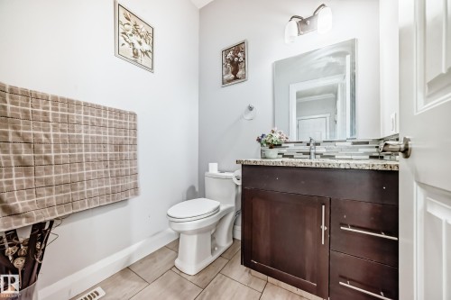 Bathroom featuring a vanity with a dark wood finish and granite countertop, a white toilet, and tiled flooring - 2 12042 101 Street, Edmonton, AB - Indoor Photo Showing Bathroom
