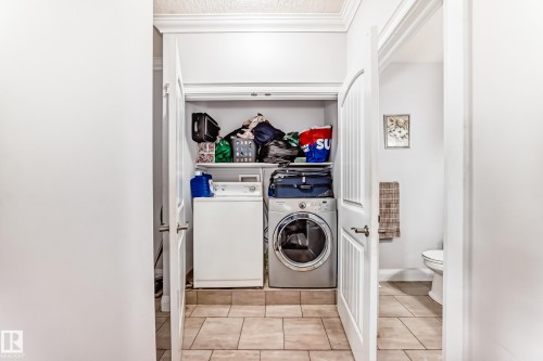Convenient laundry area featuring a white washing machine and a silver dryer, set on tiled flooring - 2 12042 101 Street, Edmonton, AB - Indoor Photo Showing Laundry Room