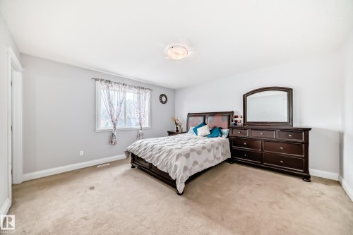 This spacious room features neutral toned carpeting and white walls, creating a bright and inviting atmosphere - 2 12042 101 Street, Edmonton, AB - Indoor Photo Showing Bedroom