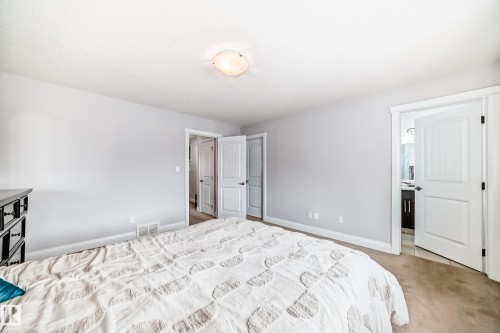 This bedroom features neutral-toned walls, light-colored carpeting, and a ceiling light fixture - 2 12042 101 Street, Edmonton, AB - Indoor Photo Showing Bedroom