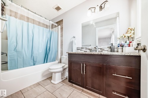 Bathroom featuring a white bathtub, a toilet, a vanity with a dark wood cabinet, a granite countertop, and a tiled backsplash - 2 12042 101 Street, Edmonton, AB - Indoor Photo Showing Bathroom