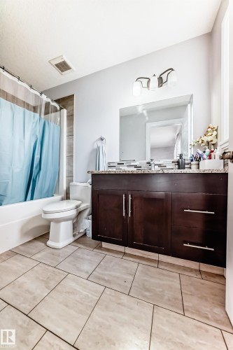 Well-appointed bathroom featuring a dark wood vanity with a solid countertop, a wall-mounted mirror, and tile flooring - 2 12042 101 Street, Edmonton, AB - Indoor Photo Showing Bathroom