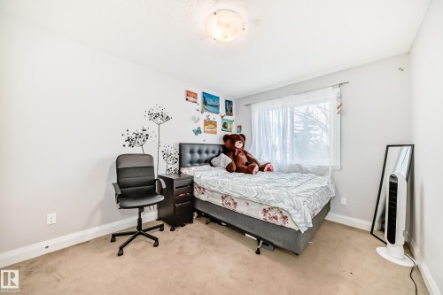 The room features light-colored walls and carpeting, a window providing natural light, and a ceiling light fixture - 2 12042 101 Street, Edmonton, AB - Indoor Photo Showing Bedroom