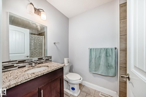 The bathroom features a modern vanity with a light-colored granite countertop, an undermount sink, and a sleek faucet - 2 12042 101 Street, Edmonton, AB - Indoor Photo Showing Bathroom