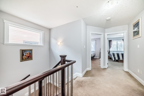 The property features an upper landing area with carpeted floors and a window providing natural light - 2 12042 101 Street, Edmonton, AB - Indoor Photo Showing Other Room