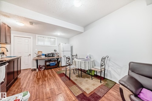 The kitchen and dining area features wood-look flooring, white walls, and a white ceiling with recessed lighting - 2 12042 101 Street, Edmonton, AB - Indoor