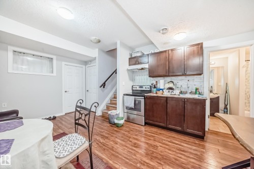 This property offers a kitchen with dark wood cabinetry, a stainless steel range, and a sink - 2 12042 101 Street, Edmonton, AB - Indoor