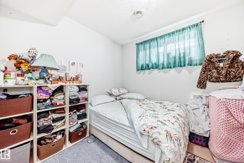 The property features a room with white walls, a window with teal curtains, and light-colored flooring - 2 12042 101 Street, Edmonton, AB - Indoor Photo Showing Bedroom