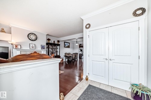 Entryway featuring white double doors with decorative paneling and tile flooring, leading into a living area with hardwood floors - 2 12042 101 Street, Edmonton, AB - Indoor Photo Showing Other Room