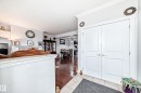 Entryway featuring white double doors with decorative paneling and tile flooring, leading into a living area with hardwood floors - 2 12042 101 Street, Edmonton, AB  - Indoor Photo Showing Other Room 