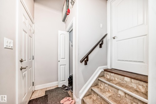 The property features a staircase with tiled steps and a dark handrail, complemented by a white paneled door at the top - 2 12042 101 Street, Edmonton, AB - Indoor Photo Showing Other Room