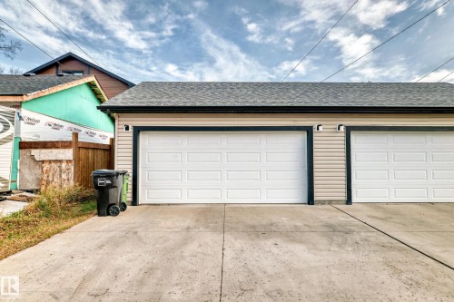 The property features a two-car garage with white panel doors and a concrete driveway - 2 12042 101 Street, Edmonton, AB - Outdoor With Exterior