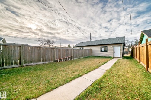 The property features a detached building with siding, a shingled roof, and a white exterior door - 2 12042 101 Street, Edmonton, AB - Outdoor