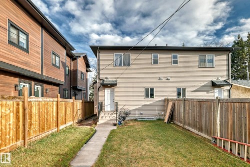 The property features a fenced yard with a grass lawn and a concrete pathway leading to a back entrance - 2 12042 101 Street, Edmonton, AB - Outdoor With Exterior