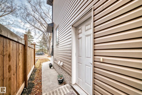 Exterior view of the property featuring horizontal siding, a side entry door, and a privacy fence - 2 12042 101 Street, Edmonton, AB - Outdoor