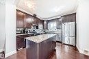 The kitchen features dark wood cabinetry, a central island with a granite countertop, and stainless steel appliances - 2 12042 101 Street, Edmonton, AB  - Indoor Photo Showing Kitchen With Stainless Steel Kitchen With Upgraded Kitchen 