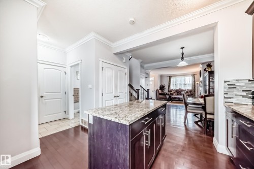 Kitchen featuring dark wood cabinetry, granite countertops, a tiled backsplash, and hardwood flooring - 2 12042 101 Street, Edmonton, AB - Indoor Photo Showing Kitchen