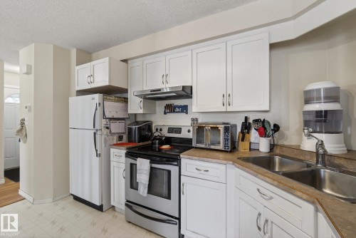 Kitchen featuring white cabinetry, a stainless steel range and range hood, and a double basin sink - 2006 Mill Woods Road E, Edmonton, AB - Indoor Photo Showing Kitchen With Double Sink