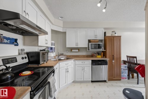 The kitchen features white cabinetry, a stainless steel dishwasher, and a built-in microwave - 2006 Mill Woods Road E, Edmonton, AB - Indoor Photo Showing Kitchen With Double Sink