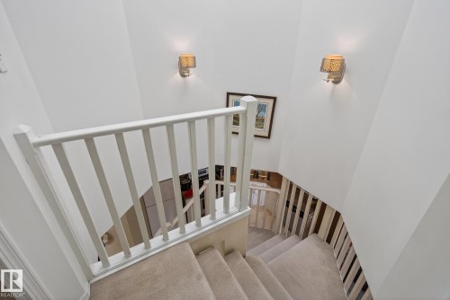 Carpeted staircase with white balusters and railings, illuminated by two wall sconces - 2006 Mill Woods Road E, Edmonton, AB - Indoor Photo Showing Other Room