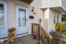 The property features a front entrance with a white storm door, accented by a wall-mounted light fixture and house numbers - 2006 Mill Woods Road E, Edmonton, AB  - Outdoor With Exterior 
