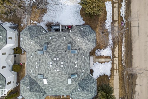 Aerial view of the property showcasing a grey shingled roof with several skylights, and a paved street and sidewalk running alongside - 2006 Mill Woods Road E, Edmonton, AB - Outdoor