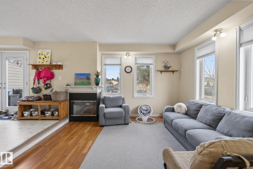 Bright and inviting living space featuring multiple windows, a decorative fireplace, and hardwood flooring - 2006 Mill Woods Road E, Edmonton, AB - Indoor Photo Showing Living Room With Fireplace