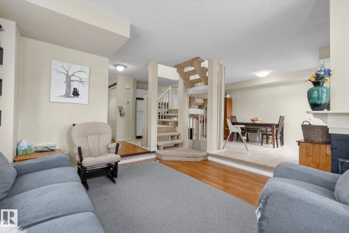 This inviting living area features hardwood flooring, a carpeted floor area, and a fireplace with a mantel - 2006 Mill Woods Road E, Edmonton, AB - Indoor Photo Showing Living Room