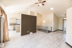 Open-concept living area featuring light wood-finish flooring, vaulted ceilings, and a ceiling fan - 