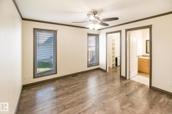 Spacious room featuring wood-finish flooring, two windows with blinds, and dark trim - 