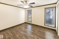 Room featuring wood-finish flooring, two window units with blinds, a ceiling fan, and contrasting trim - 