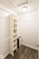 Walk-in closet featuring wood-finish flooring, built-in shelving, two hanging rods, and an overhead flush-mount light fixture - 