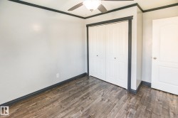 Interior space featuring wood-finish flooring, white walls, and dark trim - 