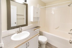 Bathroom featuring a shower-tub combination, vanity with an integrated sink, framed mirror, and upper wall cabinetry - 
