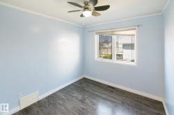 Room featuring wood-finish flooring, a ceiling fan with integrated lighting, and a window with white trim - 