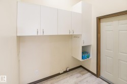 White cabinetry and a utility hookup area, featuring lighter wood-finish flooring - 