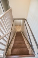 Stairwell with carpeted treads, painted balusters, and wood-finish handrail - 