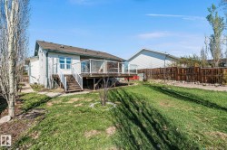 Spacious backyard featuring a wooden deck with glass panel railings, white siding, a multi-pane window, and a wooden fence - 