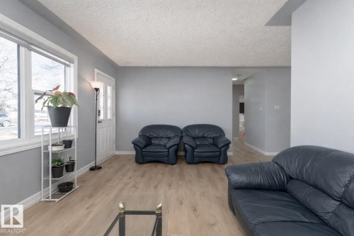 The living area features light-toned flooring, light grey walls, and a large window providing natural light - 16131 109 Avenue, Edmonton, AB - Indoor