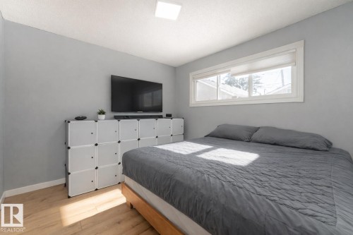This room features light wood-style flooring, a window with a roller shade, and light-colored walls - 16131 109 Avenue, Edmonton, AB - Indoor Photo Showing Bedroom