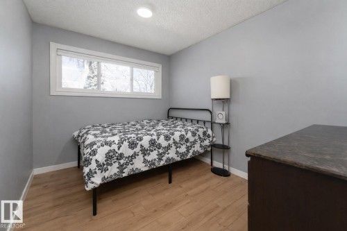 This room features light wood-style flooring, a large window, and light grey walls - 16131 109 Avenue, Edmonton, AB - Indoor Photo Showing Bedroom